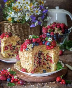 a piece of cake with berries on it sitting on a plate next to some flowers