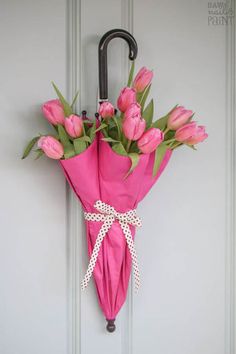 a bunch of pink tulips are tied to a door handle with an umbrella