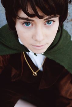 a close up of a person wearing a green and brown outfit with blue eyes,