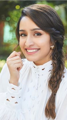 a beautiful young woman with long hair wearing a white shirt and smiling at the camera