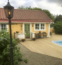 a small yellow house with a pool in the back yard and patio furniture around it