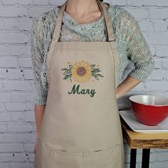 a woman wearing an apron with the word mary written on it in front of a red bowl