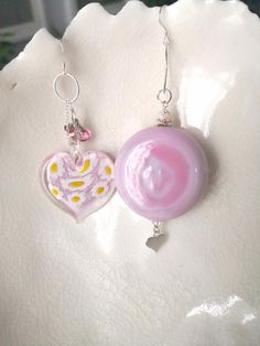 These lovely mismatched earrings are a beautiful shade of opaque pink Venetian Murano glass. The thick blown glass penny bead ( a round bead which has been partially flattened) measures approx 38mm (3.8cm or approx 1.5) and 16mm (1.6cm or 5/8")  It hangs from a Sterling silver oval hoop which in turns hangs from a Sterling silver fish hook earwire and below dangles a small Sterling silver heart. The millefiori glass heart bead measures 34mm (3.4cm or not far off 1.5") It features millefiori to t Handmade Pink Glass Jewelry, Pink Glass Round Jewelry, Pink Round Glass Jewelry, Unique Pink Round Bead Earrings, Pink Sterling Silver Round Bead Earrings, Silver Fish, Mismatched Earrings, Glass Heart, Heart Beads