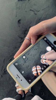 a person holding a cell phone with pictures on the screen in their hands and feet