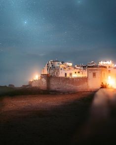 a castle lit up at night with stars in the sky