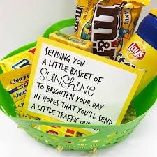 a basket filled with candy and snacks next to a sign that reads sending you a little basket of sunshine to brighten your day in hopes that you'll