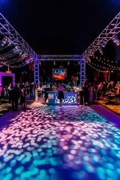 an outdoor dance floor is lit up with blue and pink lights