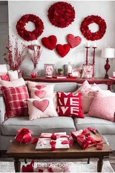 a living room filled with lots of red pillows and hearts hanging on the wall above it