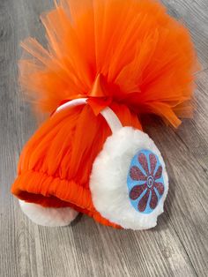 an orange and white hat with a blue flower on the top, sitting on a wooden floor