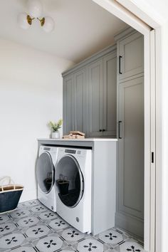 a washer and dryer in a small room with grey cabinets on the wall