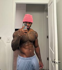 a man taking a selfie in the mirror wearing a pink hat and blue shorts