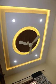 a clock mounted to the ceiling in a living room with lights on and below it