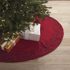 a christmas tree with presents under it on a red round tableclothed placemat