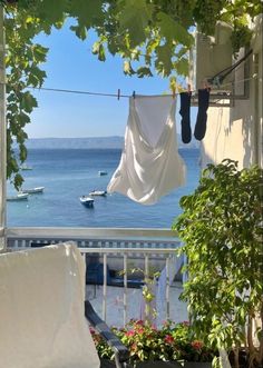 clothes hanging out to dry in the sun on a balcony over looking the water and boats