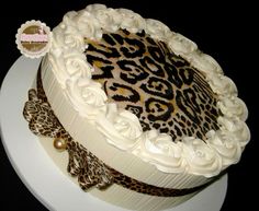 a leopard print cake with white frosting and decorations on the top, sitting on a plate