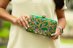 Immerse yourself in a verdant oasis with our enchanting green Gond Art clutch bags. Each piece is a canvas of nature's splendor, meticulously hand-painted with intricate designs inspired by the graceful peacock, lively sparrows, and a harmonious symphony of birds amidst lush trees. Unleash your inner art connoisseur with these dreamlike accessories, perfect for elevating your evening ensemble. Gond Art, a timeless tradition from Madhya Pradesh, India, breathes life into our clutches through its Artistic Green Rectangular Shoulder Bag, Hand Painted Green Bags For Everyday, Green Hand-painted Bag As Gift, Everyday Use Hand Painted Green Bags, Green Bohemian Clutch For Everyday Use, Green Hand Painted Bags For Gift, Artistic Green Shoulder Bag As Gift, Hand Painted Green Bags For Gift, Green Hand Painted Rectangular Shoulder Bag