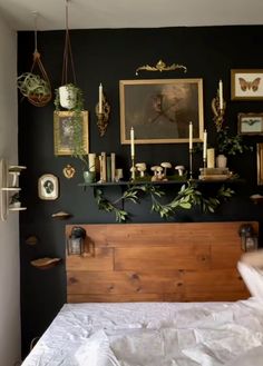 a bedroom with black walls and pictures on the wall above the headboard, along with candles