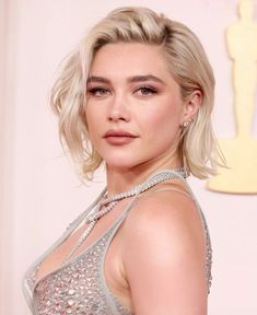 a woman with blonde hair wearing a silver dress and diamond necklaces on her neck