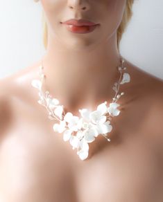 a woman wearing a necklace with white flowers on it