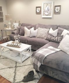 a living room filled with furniture and pillows on top of a white rug in front of a gray couch