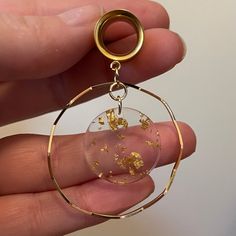 a person is holding a small glass ball with gold flakes in it