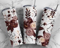 three white and brown floral tumblers sitting on top of a marble counter next to each other