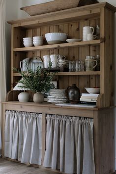 a wooden hutch filled with dishes and cups