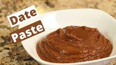 a white bowl filled with brown paste on top of a counter next to a sign that says date paste