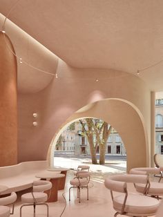 the interior of an office building with white furniture and large arched doorways leading to trees