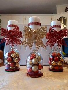 three glass vases with ornaments in them on a table