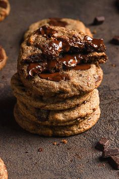 chocolate chip cookies stacked on top of each other with one broken cookie in the middle