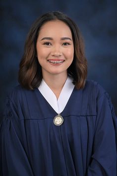 a woman in a graduation gown smiles for the camera while wearing a badge on her cap and gown