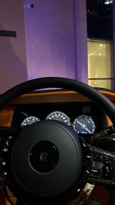 the interior of a car with gauges and steering wheel in front of a purple building