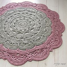 a crocheted doily is shown on the floor in pink, gray and white