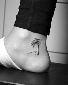 a small palm tree tattoo on the side of a woman's foot, which has a wave coming out of it