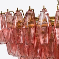 many pink glass vases are hanging from a light fixture