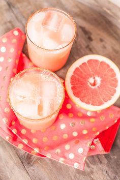 two grapefruit cocktails sitting next to each other on a red and gold napkin