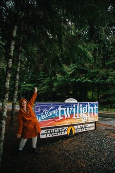 a woman in an orange jacket standing next to a sign