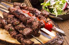 steak skewers with tomatoes and lettuce on a cutting board