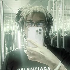 a man with dreadlocks taking a selfie in front of his cell phone