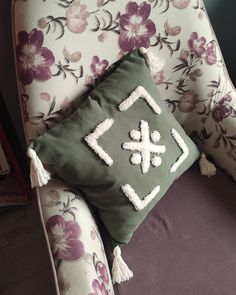 a green pillow sitting on top of a chair next to a purple flowered wall