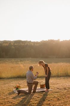 a man kneeling down next to a woman on top of a field