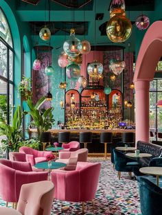 the interior of a restaurant with pink and blue chairs, green walls and chandeliers