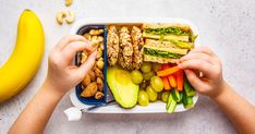 two hands grabbing food from a container with fruits and vegetables in it, next to a banana