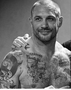 a black and white photo of a man with tattoos on his chest