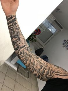 a man with a tattoo on his arm is taking a selfie in the mirror