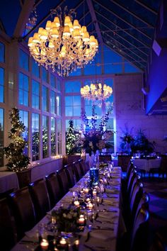 the dining room is lit up with candles and christmas trees in front of large windows