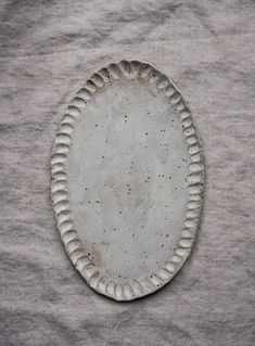 a white plate sitting on top of a gray cloth covered tablecloth with holes in the middle