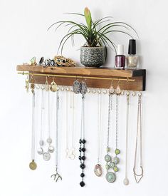 a wooden shelf filled with lots of necklaces and jewelry hanging from it's sides