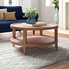 a living room with a blue couch, coffee table and rug on the wooden floor